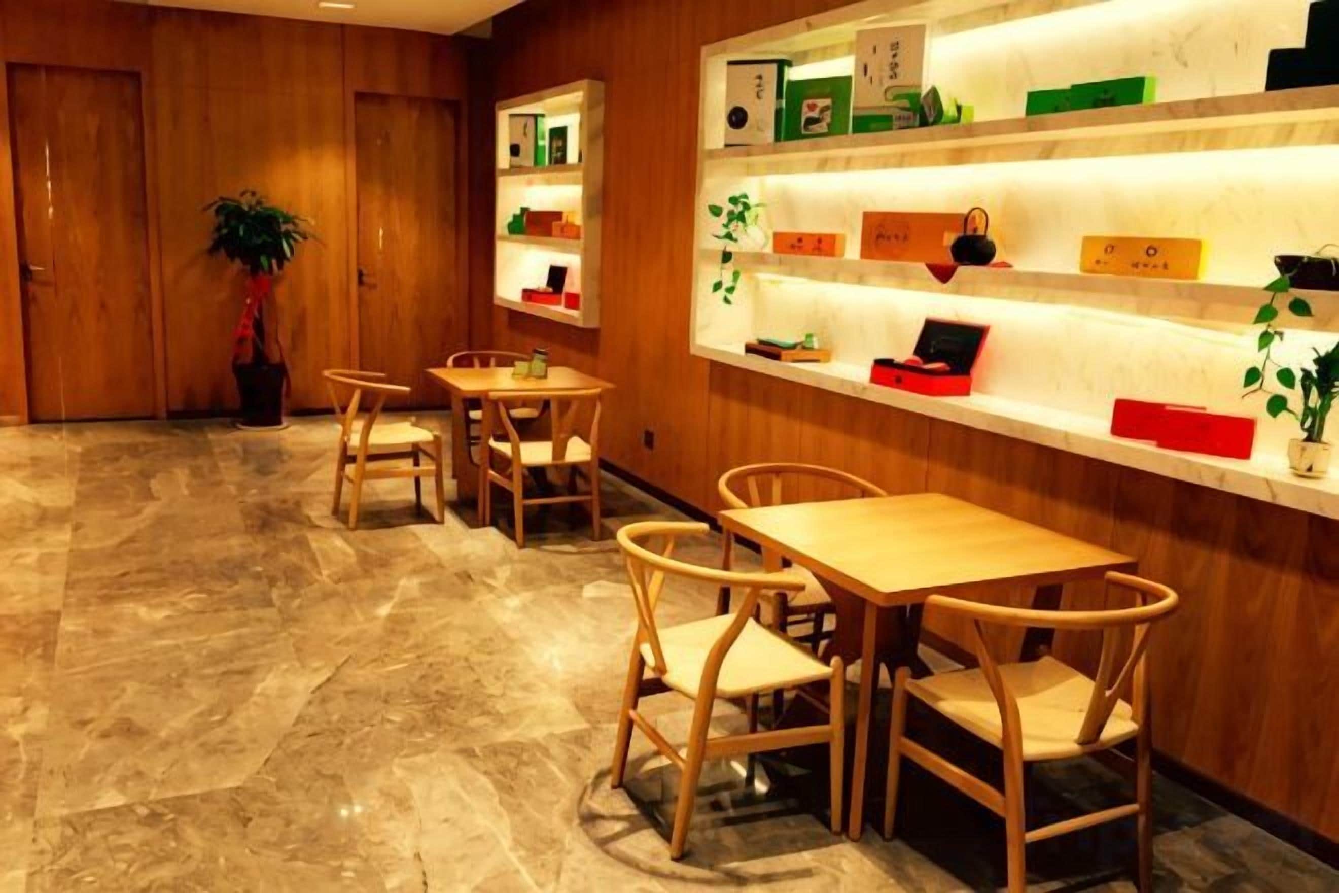 Un vestíbulo de hotel con suelo de madera, una recepción y varias mesas y sillas de madera.