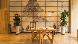 Une pièce de style japonais traditionnel, avec un sol recouvert de tatamis, une petite table en bois et un grand paravent shoji orné d’une peinture représentant un paysage de montagne.
