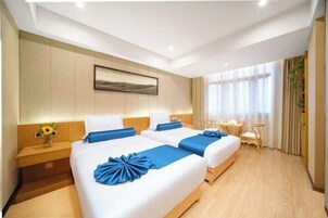 Una habitación de hotel con dos camas, un escritorio, una silla y una ventana con cortinas.