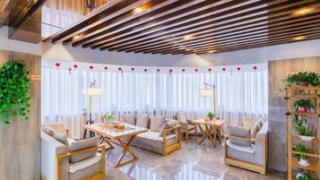 A modern hotel lobby with seating arrangements, a coffee table, and a plant shelf.