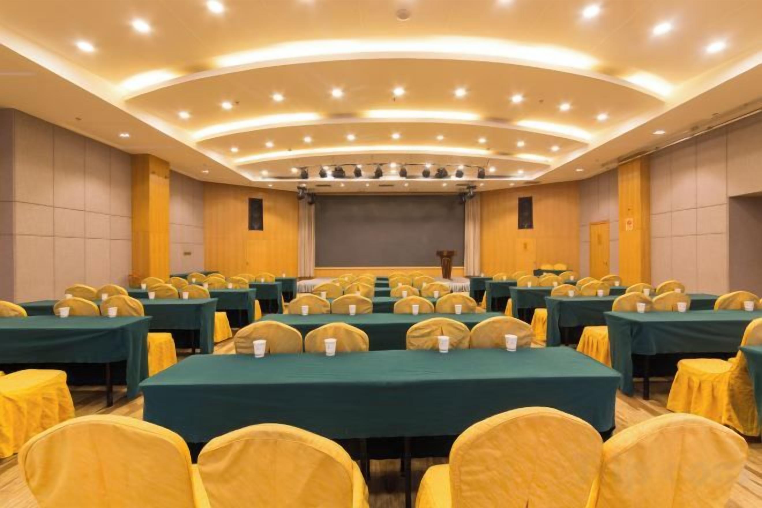 A conference room with multiple tables and chairs, a stage with a screen, and a podium.