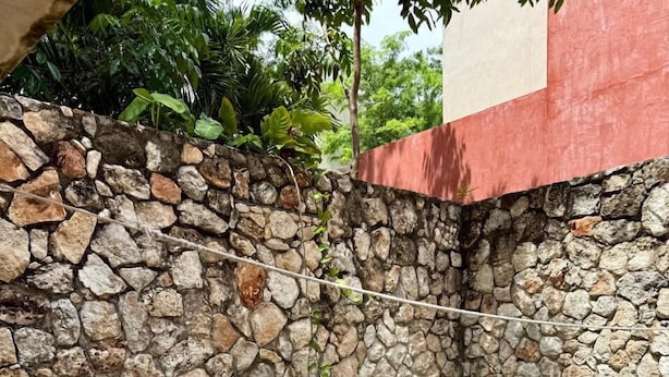 A swimming pool with a stone wall and a tiled deck area. - Unahana Hotel Boutique & villas (Valladolid)