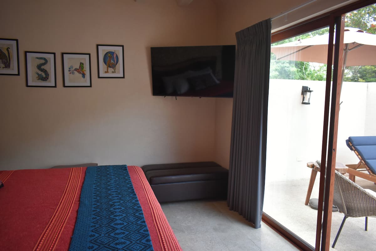 Une chambre avec un lit, une tél évision et une porte-fenêtre coulissante donnant sur un espace extérieur aménagé pour se détendre.