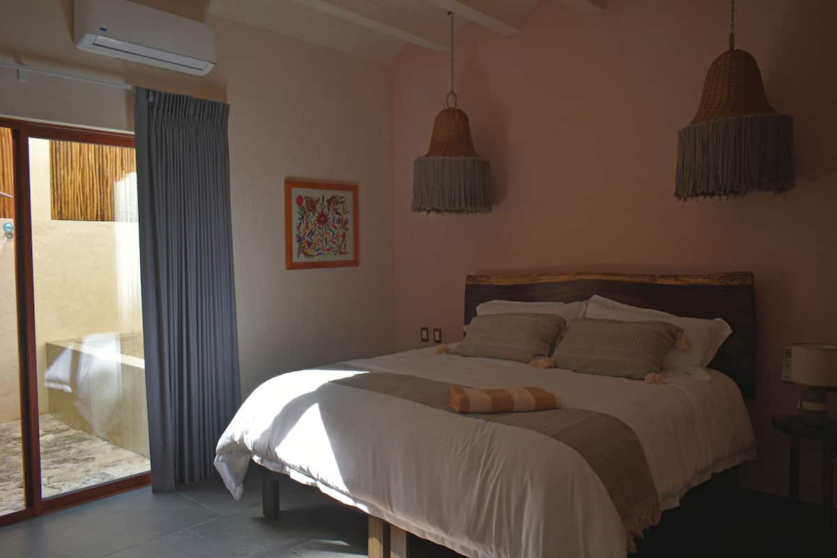 A bedroom with a large bed, a sliding glass door, and two hanging lamps.