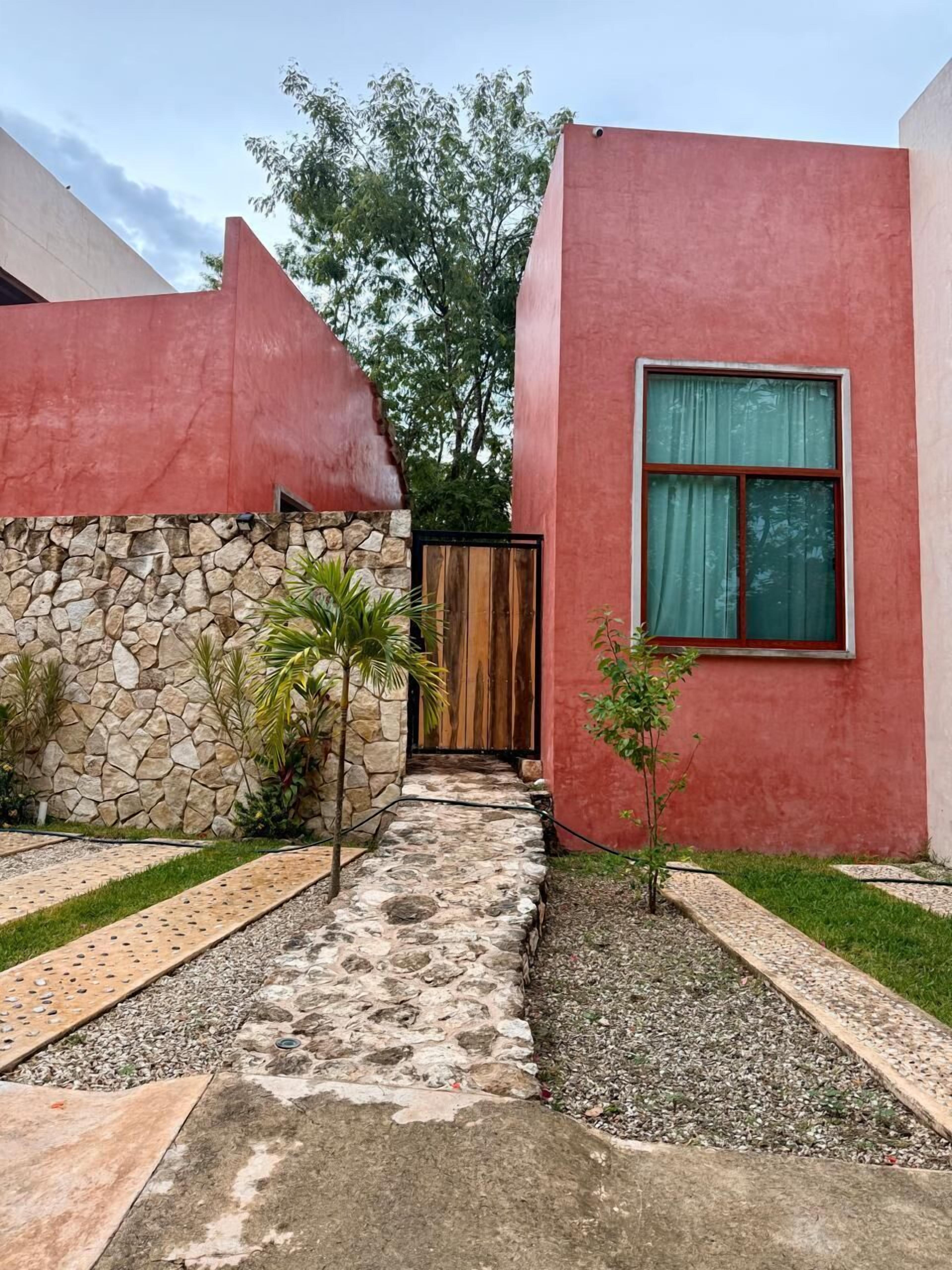 Un bâtiment rouge avec un mur en pierre, une porte en bois et un chemin pavé.