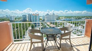 A balcony with wicker chairs and a table, overlooking a cityscape with high-rise buildings and a clear sky. - Fort Lauderdale Beach Resort 1 Bedroom Suite; RATES ARE NEGOTIABLE!!! (Fort Lauderdale)
