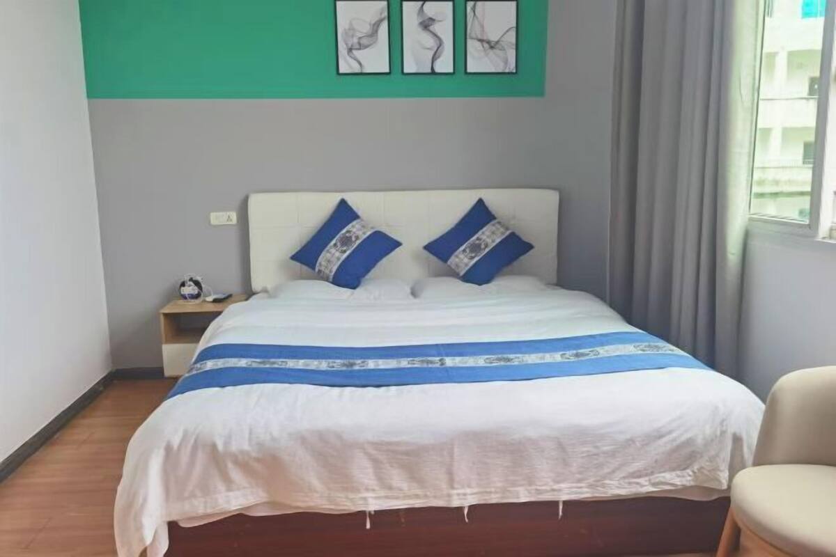 A neatly made bed with a white and blue bedspread, two matching pillows, and a small bedside table with a lamp.