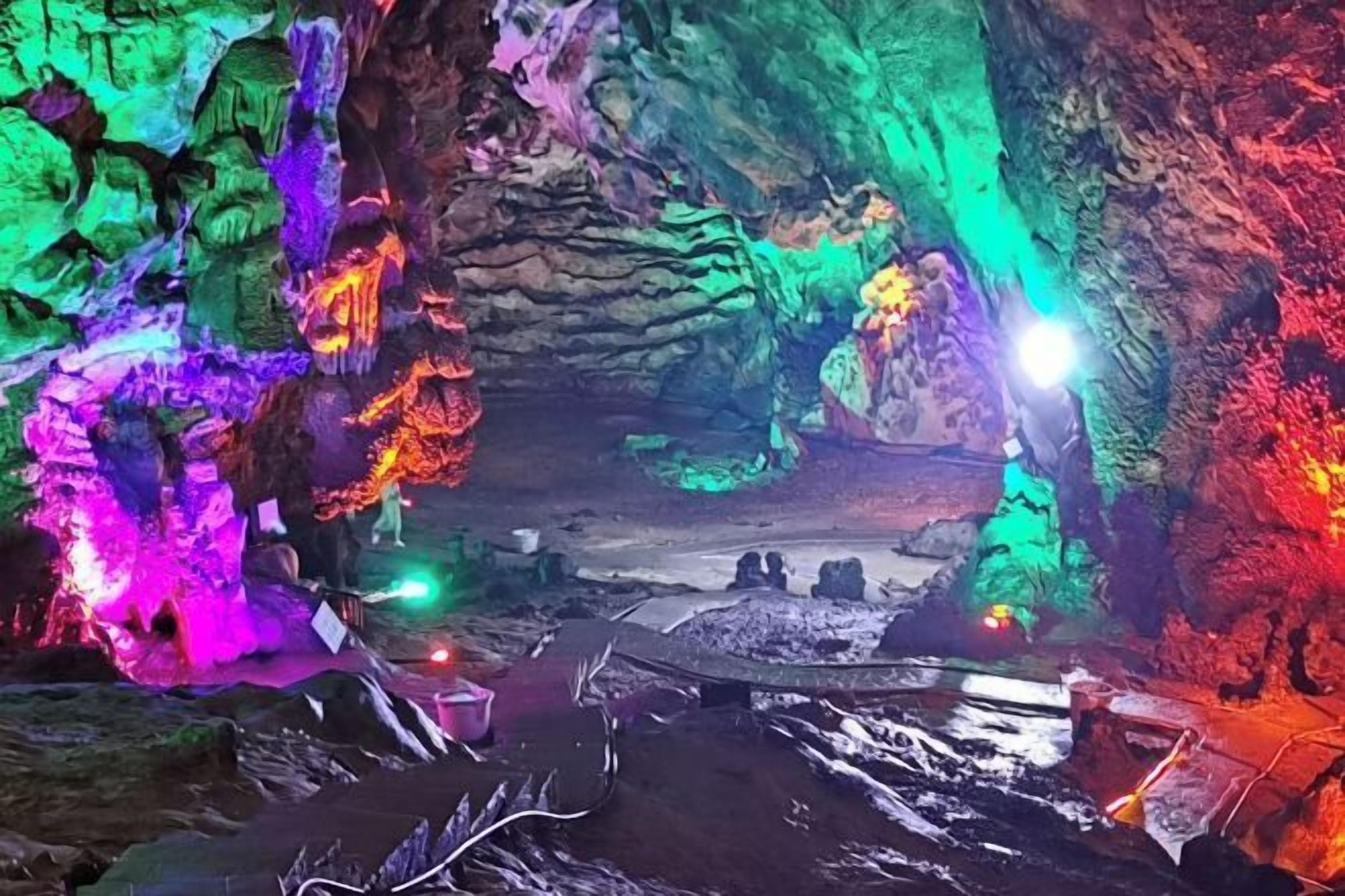 A cave with colorful lighting and a pathway leading through it.