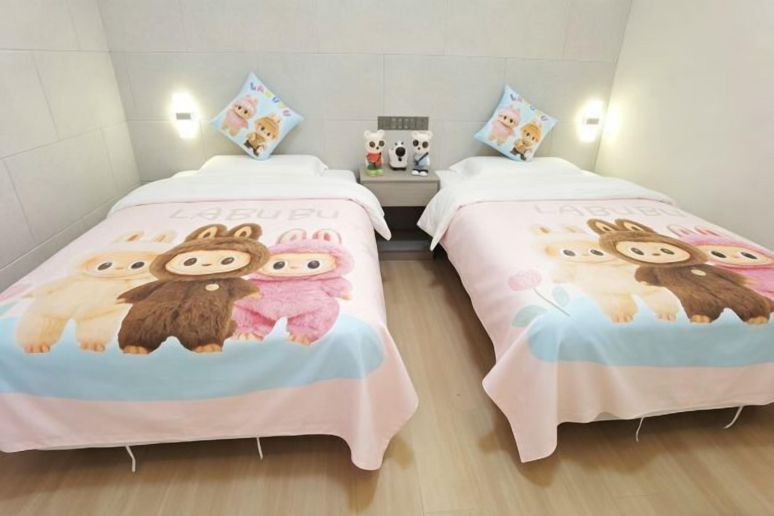 Two single beds with matching bedding, a nightstand with a lamp, and wall-mounted lights.