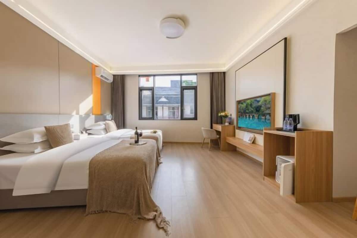 A hotel room with a bed, bedside tables, a desk, a chair, a TV, and a window.
