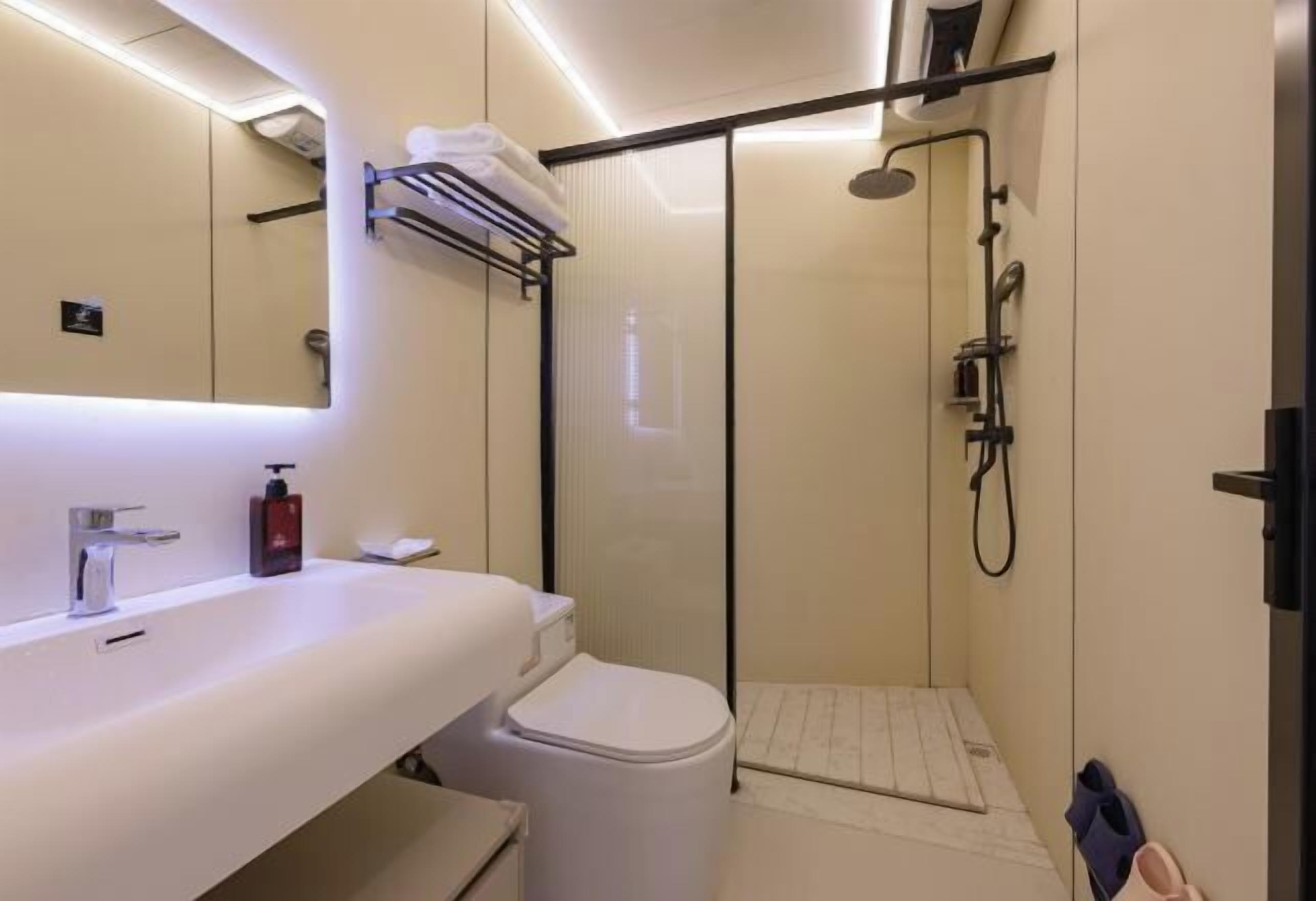 Ein modernes Badezimmer mit Waschbecken, Toilette und Dusche, alles in Weiß.