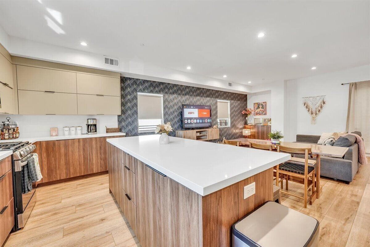 Een moderne keuken met houten kastjes, een centraal eiland en een zithoek met een tafel en stoelen.