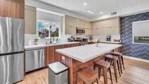Een moderne keuken met een centraal eiland, roestvrijstalen apparatuur en houten kastjes.
