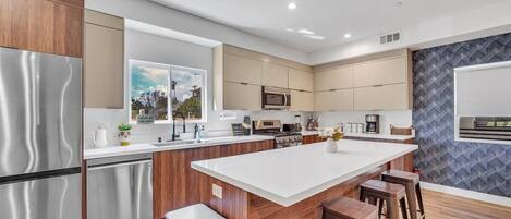 Una cocina moderna con una isla central, electrodomésticos de acero inoxidable y armarios de madera.