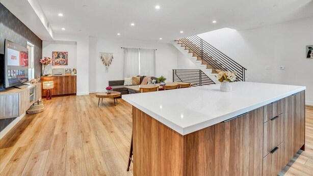 Een moderne keuken met een centraal eiland, houten vloeren en een trap naar een hoger niveau.