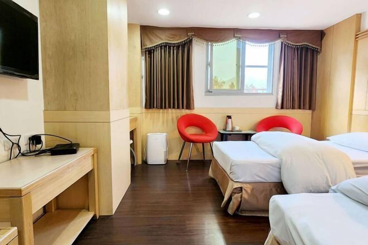 Een hotelkamer met een bed, bureau, stoel, televisie en raam met gordijnen.