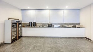 Una cocina moderna con una isla central, electrodomésticos integrados y un refrigerador con puerta de vidrio.
