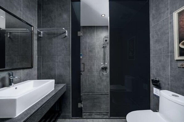 Ein modernes Badezimmer mit einem weißen Waschbecken, einer Duschkabine aus Glas und einer Toilette.
