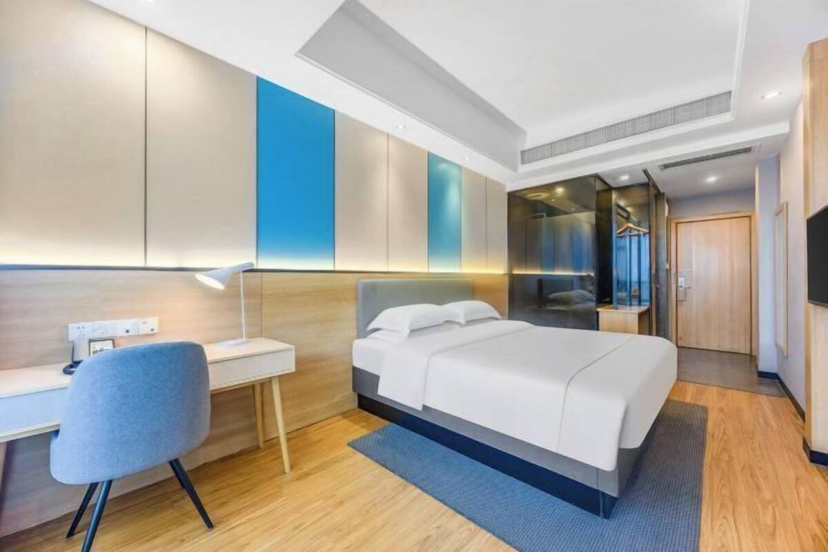 Ein modernes Hotelzimmer mit Bett, Schreibtisch, Stuhl und Fernseher.