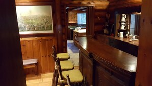 Un intérieur en bois avec un bar, des tabourets et un tableau accroché au mur.