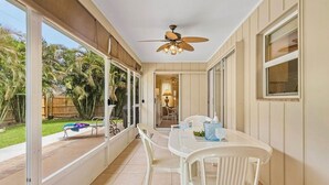 A covered patio with a dining table and chairs, large windows, and a ceiling fan. - Dolphin Sands Retreat (Venice)