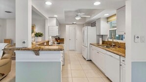 A modern kitchen with white cabinetry, granite countertops, and a central island. - Dolphin Sands Retreat (Venice)