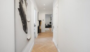 A hallway with white walls, a wooden floor, and a door leading to a room. - City Centre Apartment with 2 Private Car Spaces (Edinburgh)