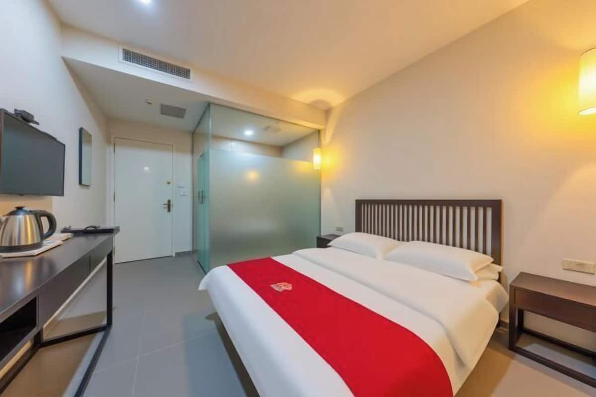 Une chambre d’hôtel moderne équipée d’un lit, d’une table de chevet et d’un téléviseur fixé au mur.