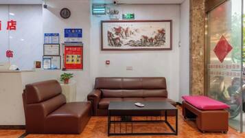 A hotel reception area with a reception desk, seating area, and a framed artwork on the wall.