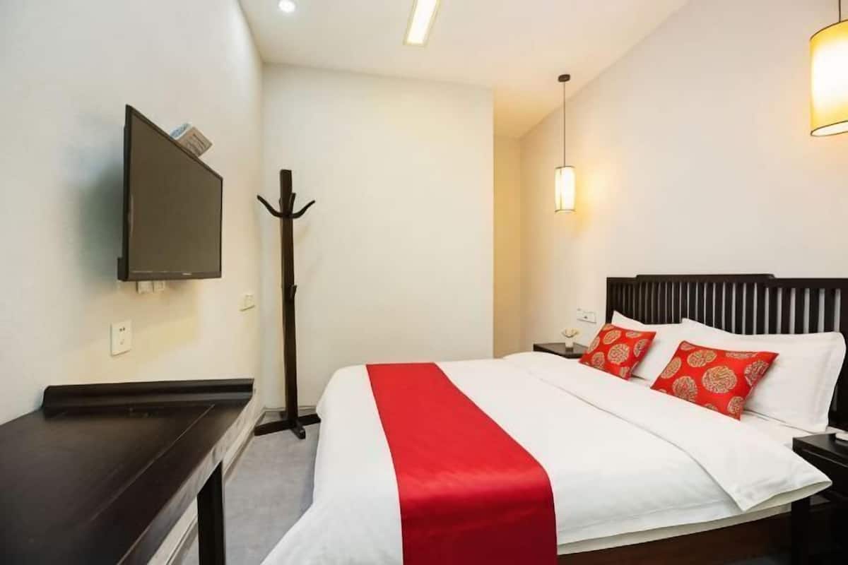 Une chambre d’hôtel équipée d  ’un lit, d’un téléviseur fixé au mur, d’un porte-manteau et d’une table de chevet.