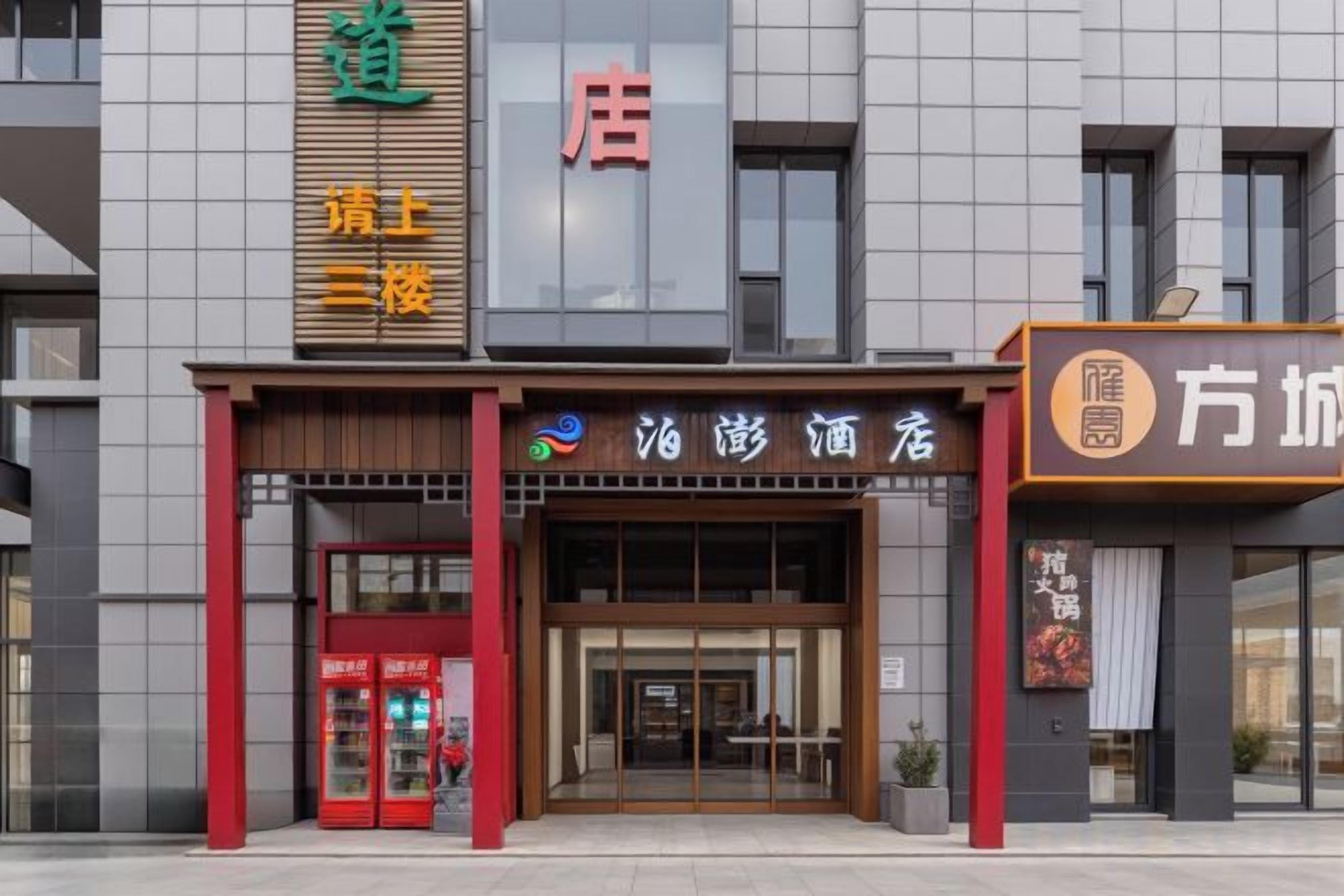 A hotel entrance with a modern facade, a red and brown color scheme, and a visible entrance door.
