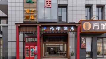 A hotel entrance with a modern facade, a red and brown color scheme, and a visible entrance door.