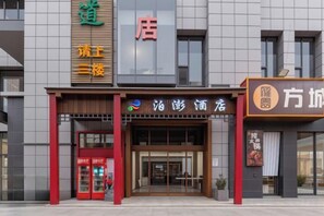 A hotel entrance with a modern facade, a red and brown color scheme, and a visible entrance door. - Yunshang Holiday Hotel (Zhengzhou Erqi Wanda Branch) (Zhengzhou)