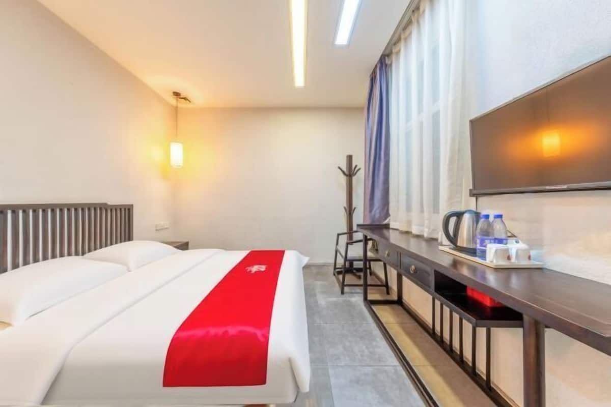 Une chambre d’hôtel équipée d’un lit, d’un bureau, d’une chaise, d’une télévision et d’une fenêtre avec des rideaux.
