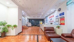 A reception area with a reception desk, seating area with leather sofas, and potted plants.
