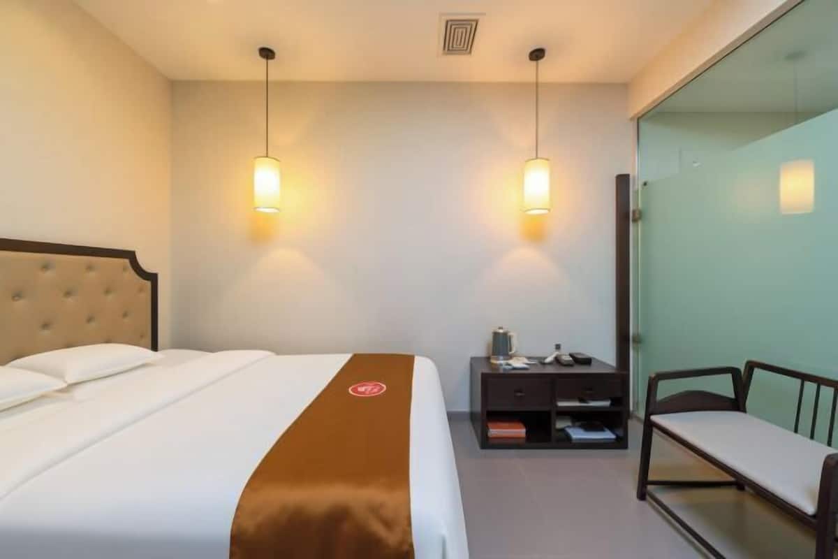 Une chambre d’hôtel comprenant un lit, une table de chevet, une chaise et une cloison en verre.