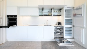 A modern kitchen with white cabinetry, a built-in oven, a dishwasher, and a refrigerator. - Luxury Central Suite Garden in Lugano (Lugano)