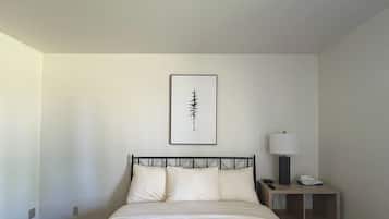 A hotel room with a bed, a bedside table with a lamp, and a framed picture on the wall.