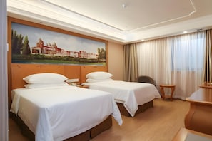 Ett hotellrum med två sängar, en målning av en byggnad, ett skrivbord och en stol.