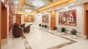 Um saguão de hotel com piso de mármore, área de estar e obras de arte nas paredes.