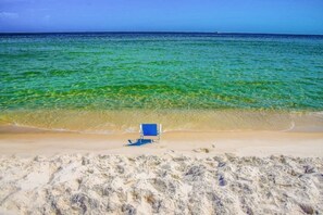 Una playa con agua turquesa cristalina y una sola silla de playa azul.