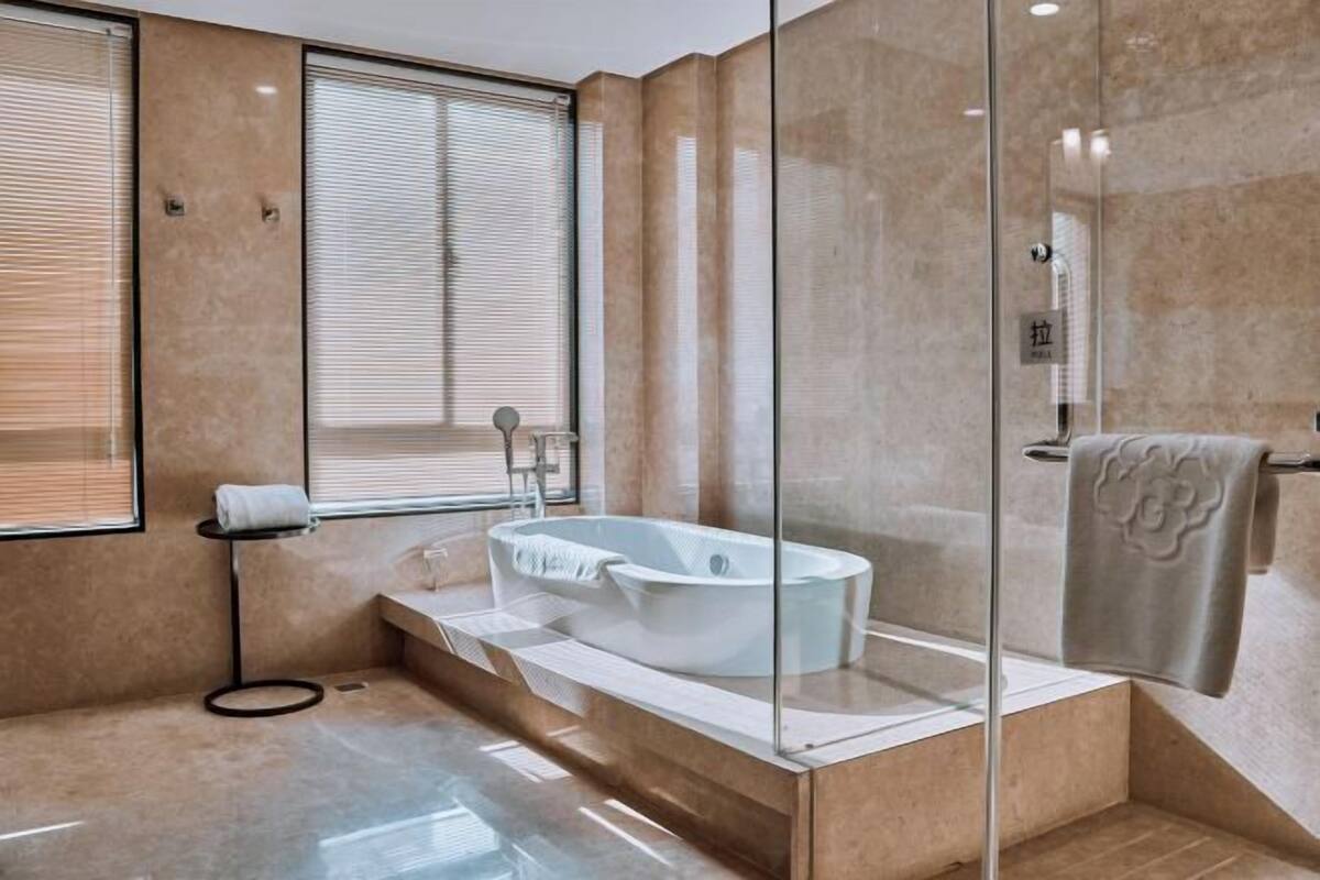 A modern bathroom with a freestanding bathtub, a glass shower enclosure, and a towel rack.
