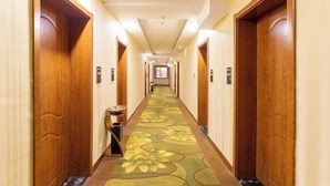 En hotels korridor med trædøre, et blomstret gulvtæppe og et lyst lofter.