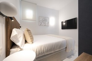 Una camera da letto moderna con un letto, una TV a schermo piatto, un'opera d'arte incorniciata e una testiera in legno.