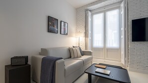 A modern living room with a sofa, a coffee table, a lamp, and a speaker. - Reina Sofia Center (Madrid)