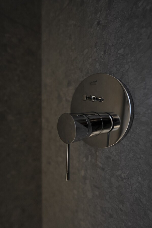 Un bagno moderno con un rubinetto metallico elegante fissato a una parete strutturata.