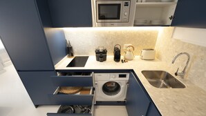 A compact kitchen with a microwave, toaster, sink, and built-in washing machine. - Reina Sofia Center (Madrid)