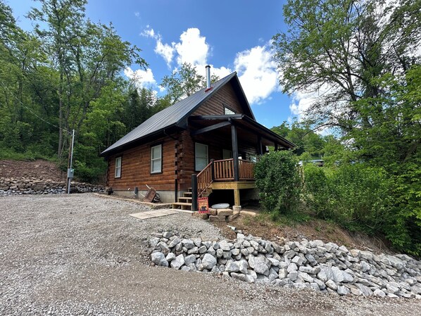 A log cabin with a porch and a stone foundation.