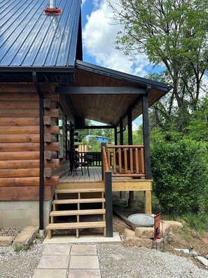 A log cabin with a wooden deck, outdoor seating, and a metal roof. - Rosie's Cabin is an authentic log cabin located just 10 minutes from Charleston. (South Charleston)