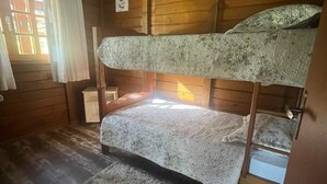 A bunk bed room with wooden walls, a window with curtains, and a rug on the floor. - Pousada Rancho Queimado (Aguas Mornas)